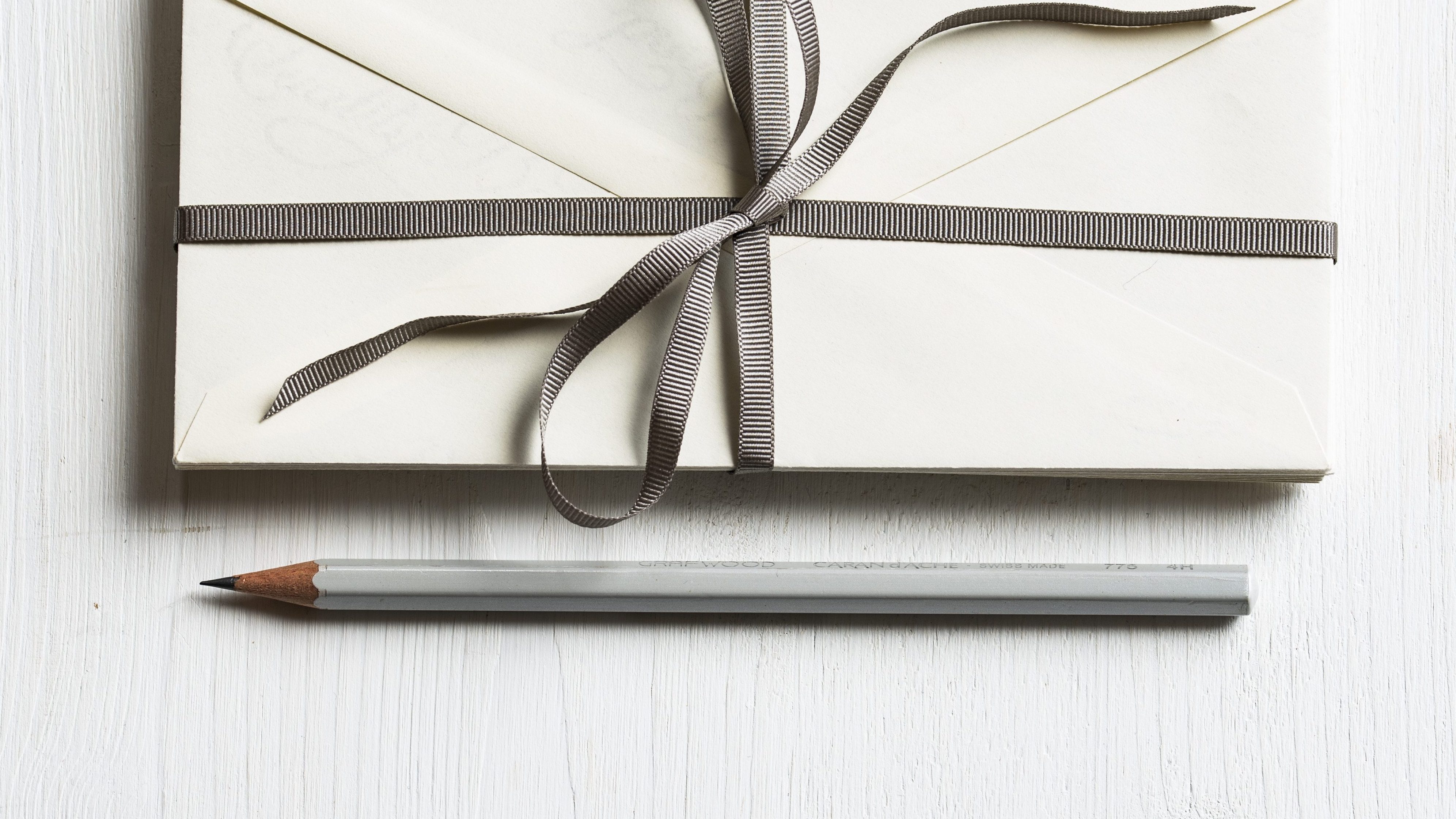 submission envelopes wrapped with a bow tie and gray pencil underneath, ready to write more